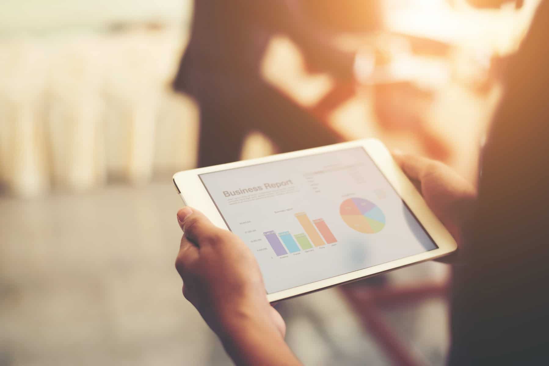 Person'd hand holding tablet with financial charts including unrelated business income tax