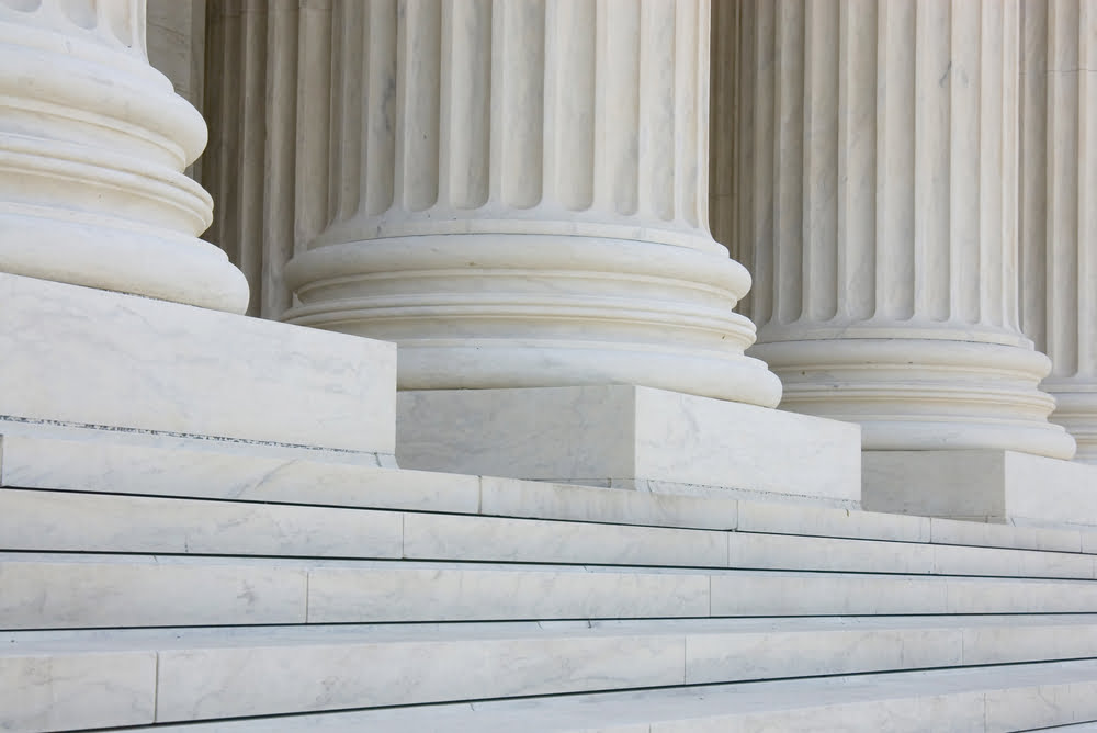 Close-up view of marble columns and steps, showcasing classical architectural design with large, fluted columns and expansive stone steps leading up to an unseen structure, reminiscent of the formalities observed in nonprofit filing requirements.
