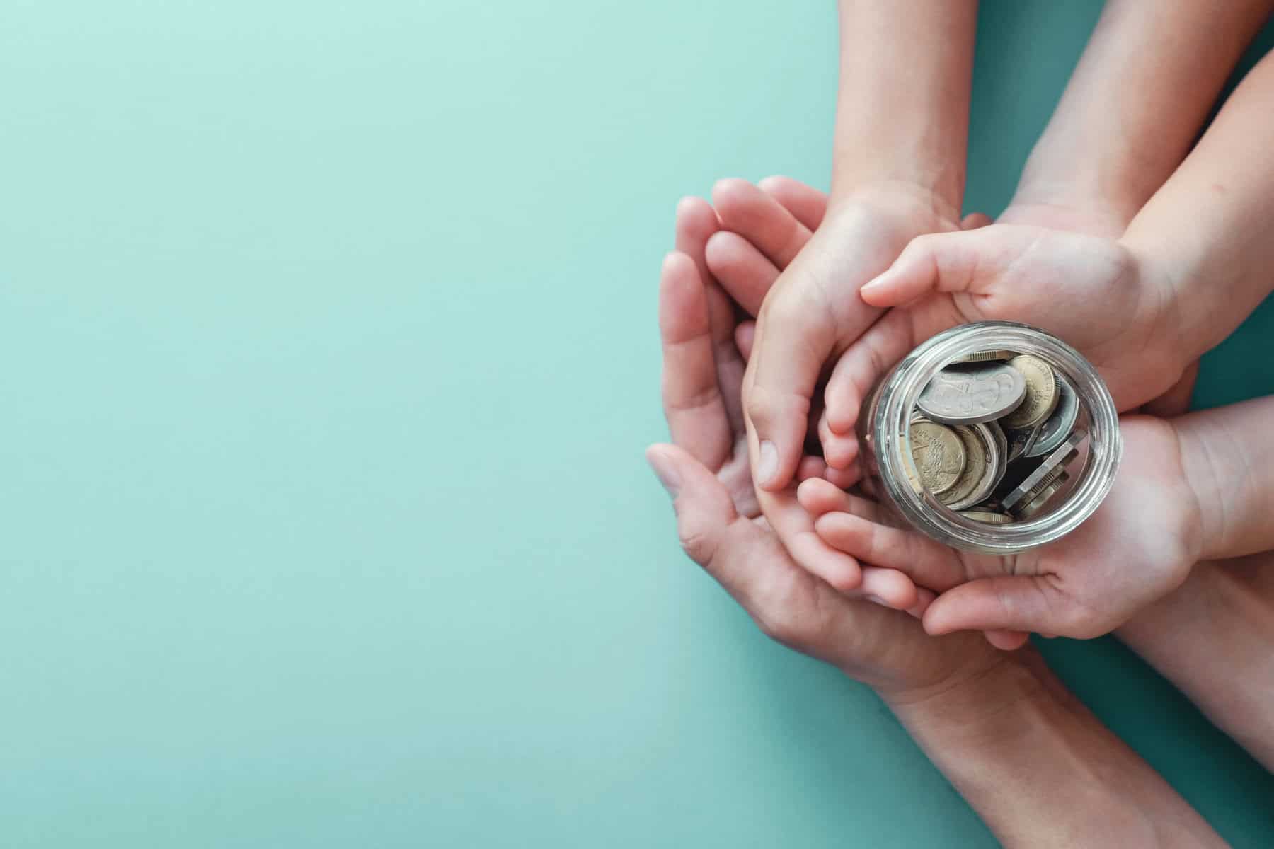Child and adult hands holding money Jar, shows Donations and Fundraising for Charity
