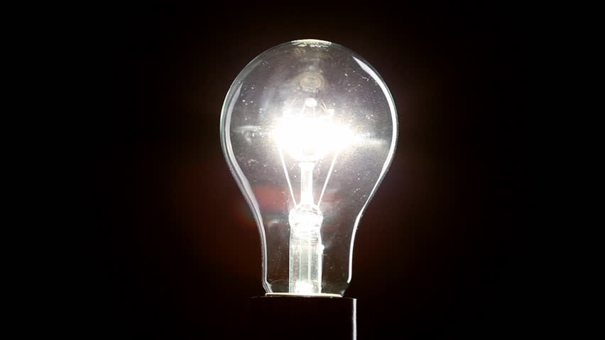 A bright, illuminated incandescent light bulb against a dark background.