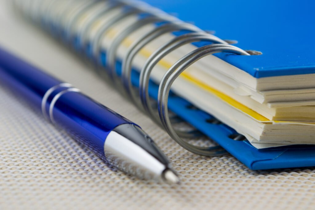 Close-up of a blue pen and a spiral-bound notebook, ready to write your nonprofit mission statement.